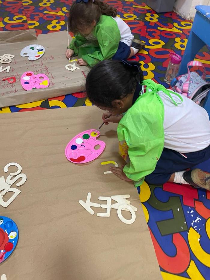 Niñas pintando letras sobre papel kraft